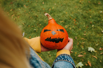 Halloween pumpkin. Woman holding a scary face pumpkin. Happy Halloween party holiday. Celebrate...