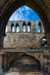 Through a pointed arch, the remains of an old abandoned cathedral can be seen