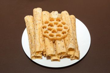 Side view of Kerala dessert Kuzhalappam and Achappam in a plate on brown background 