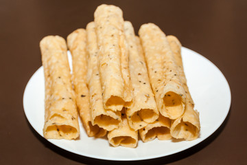 Side view of Kerala dessert Kuzhalappam in a plate on brown background 