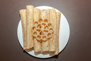 Top view of Kerala dessert Kuzhalappam and Achappam in a plate on brown background 
