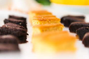 Close up of a tray of pieces of chocolate and lemon cake, against a bokeh background