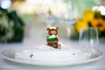 Close up of a tiny placeholder shaped like a bride female bear against a bokeh background