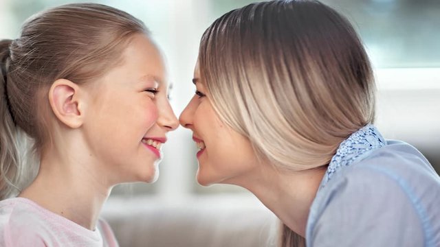 Pretty family young mother and child daughter smiling with open mouth showing teeth playing touching nose