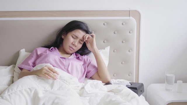 Sick young woman having headache while lying on the bed at home. Shot in 4k resolution
