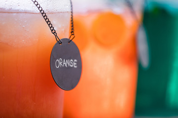 Close up of two jugs of juice, orange in the foreground and mint in the background