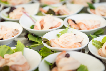 Close up of a tray of appetizers made up of shrimps and mayonnaise, and adorned with green leaves