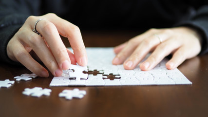 hand pick a piece of jigsaw to connect success on wooden table top selected focus