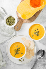 Creamy pumpkin cream soup with seeds. Autumn dish. Light grey background. Top view