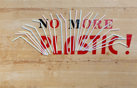 Environmental awareness care shot. It straws on red and black wooden background with motto no more plastic. - Powered by Adobe