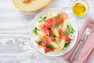 Melon and prosciutto ham salad with Mozzarella and arugula leaves.