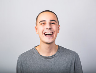 Happy fun young man laughing with wide opened mouth in casual clothing on blue background with empty copy space.