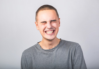 Happy fun young man laughing with wide opened mouth in casual clothing on blue background with empty copy space.