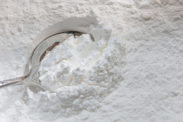 Close-up of tapioca starch or flour powder in wooden spoon on white background