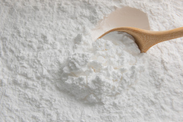 Close-up of tapioca starch or flour powder in wooden spoon on white background
