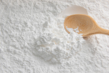Close-up of tapioca starch or flour powder in wooden spoon on white background