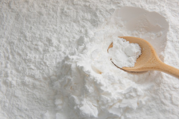 Close-up of tapioca starch or flour powder in wooden spoon on white background