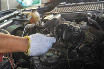 The mechanic's hand is fixing the engine under the car.