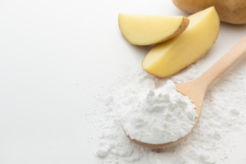 Close-up of potato starch or flour powder in wooden spoon on white background