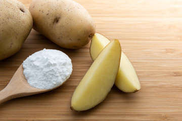 Close-up of potato starch or flour powder in wooden spoon on wooden table background