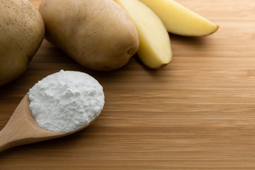Close-up of potato starch or flour powder in wooden spoon on wooden table background