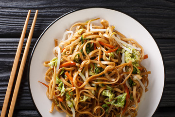 Homemade fried chow mein noodles with Chinese vegetables close-up on a plate. Horizontal top view