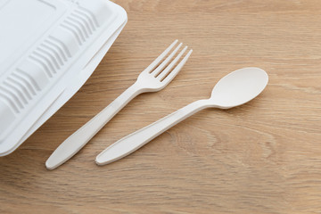 Biodegradable plastic spoon, fork and knife made from starch on wooden background