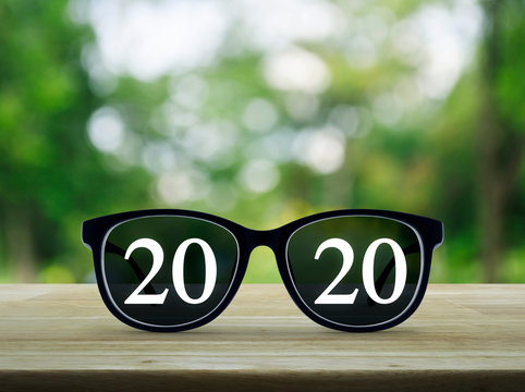 2020 White Text With Black Eye Glasses On Wooden Table Over Blur Green Tree In Park, Business Vision Happy New Year 2019 Concept