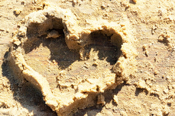 A child's heart fashioned from wet sand on a wooden background.