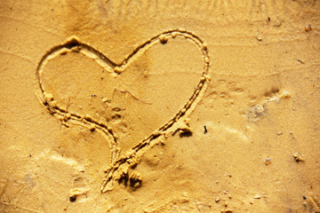 Drawing of a heart on a yellow sandy beach.