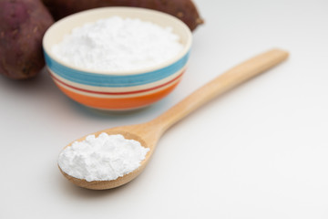 Fototapeta na wymiar Close-up of potato starch or flour powder in wooden spoon on white background