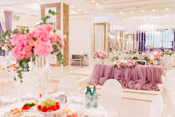 Table decoration with fresh flowers in pastel colors. Elegant dining table in peach-pink color. Luxurious flowers composition. Indoors wedding. Tablecloth lilac color. Beautiful table setting.