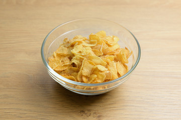 Close-up of starch or flour powder in wooden spoon with cornflakes on wooden background
