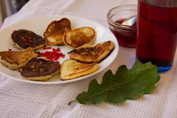 fritters on a white plate watered with berry jam. dessert on a white tablecloth