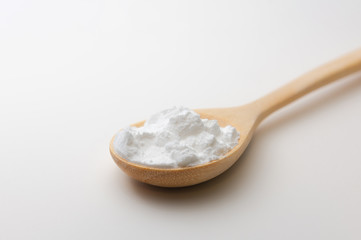 Close-up of tapioca starch or flour powder in wooden spoon on white background