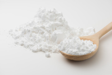 Close-up of tapioca starch or flour powder in wooden spoon on white background