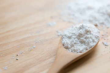 Close-up of tapioca starch or flour powder in wooden spoon with wooden background