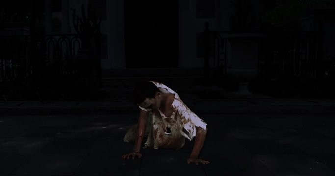 Scary zombie man crawling on the dark spooky house yard at night. Halloween Concept. Shot in 4k resolution