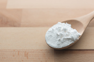 Close-up of tapioca starch or flour powder in wooden spoon on white background