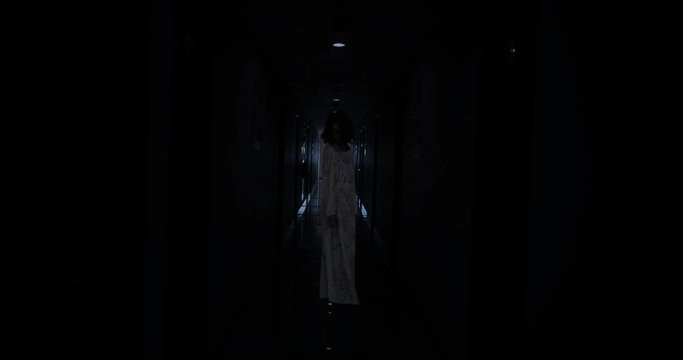 Creepy zombie woman walking in the dark hospital aisle at night. Shot in 4k resolution