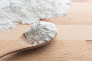 Close-up of tapioca starch or flour powder in wooden spoon on white background