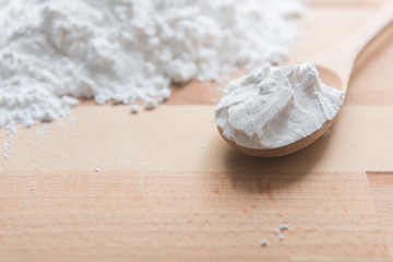 Close-up of tapioca starch or flour powder in wooden spoon on white background