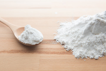 Close-up of tapioca starch or flour powder in wooden spoon on white background