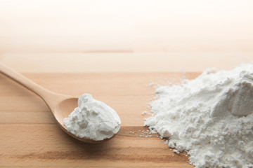 Close-up of tapioca starch or flour powder in wooden spoon on white background