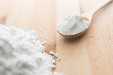 Close-up of tapioca starch or flour powder in wooden spoon on white background