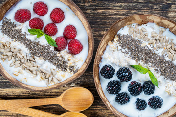 Smoothie in coconut bowl with blackberries, raspberries, oatmeal, sunflower seeds and chia seeds for breakfast , close up. The concept of healthy eating, superfood