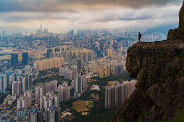 A tourist man standing on Suicide cliff in Hong Kong Downtown, China. Financial district and business centers in technology smart city in Asia. Skyscraper and high-rise buildings at sunset.
