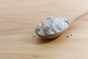 Close-up of tapioca starch or flour powder in wooden spoon with wooden background