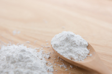 Close-up of tapioca starch or flour powder in wooden spoon with wooden background