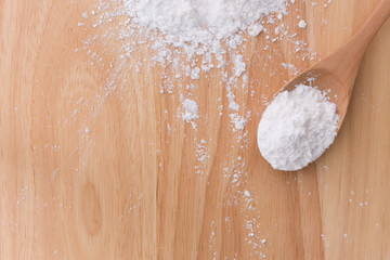 Close-up of tapioca starch or flour powder in wooden spoon with wooden background